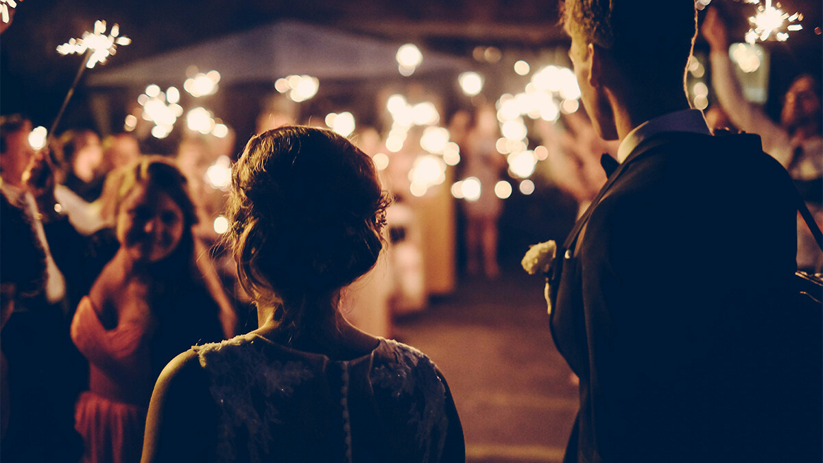 Hochzeitspaar steht vor ihren Freunden die Lichterkerzen hochhalten