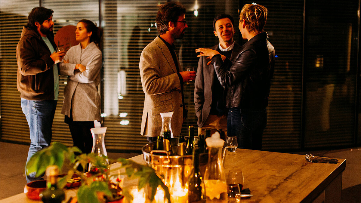 Männer sprechen hinter einem Tisch mit leeren Weinflaschen
