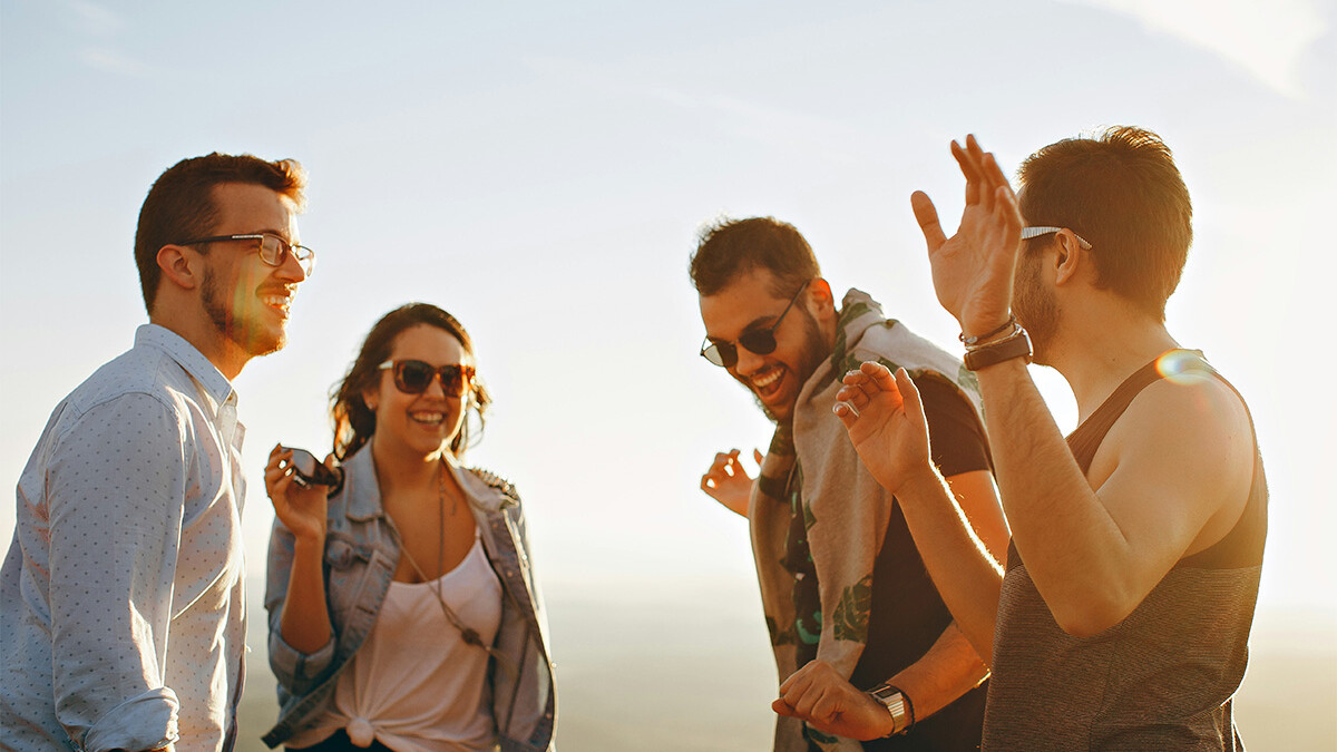 Vier junge Menschen mit Sonnenbrillen stehen in der Sonne