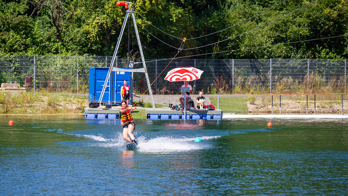 Wakeboarderin mit Leihmaterial lernt Wakeboard fahren